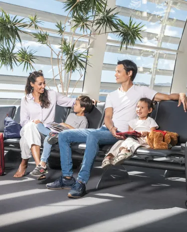 Famille assise sur un banc en salle d'embarquement